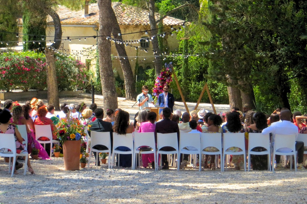 Guests sitting during a secular ceremony under the pines - L'ombrière